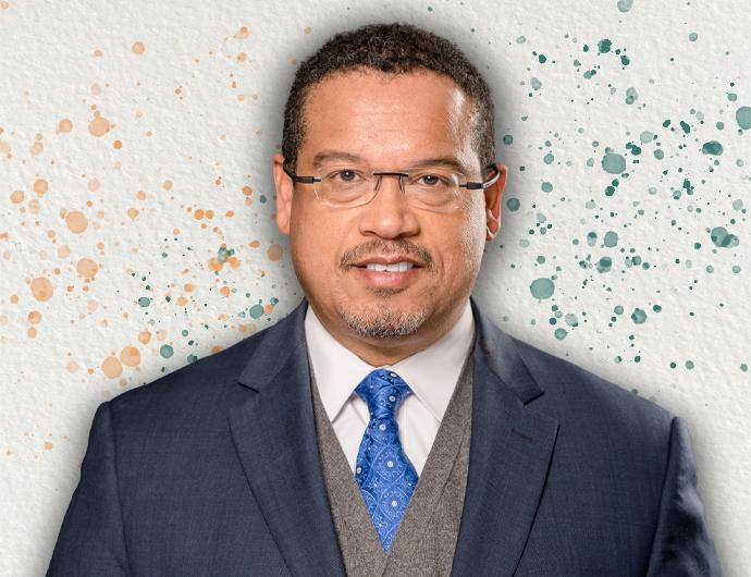 Headshot of AG Ellison in navy suit with blue tie and vest, over top an off-white background with orange and green spatter
