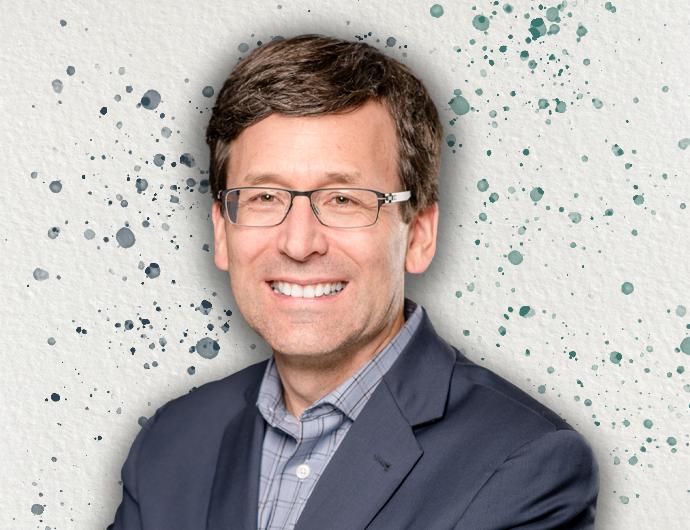 Headshot of AG Bob Ferguson in a grey suit, overtop an off-white background with blue and green spatter