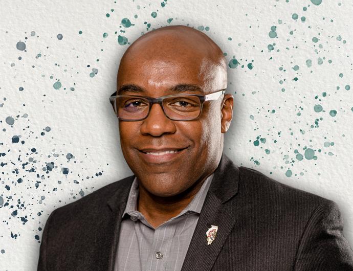Headshot of AG Kwame Raoul in a dark brown suit, overtop an off-white background with blue and green spatter