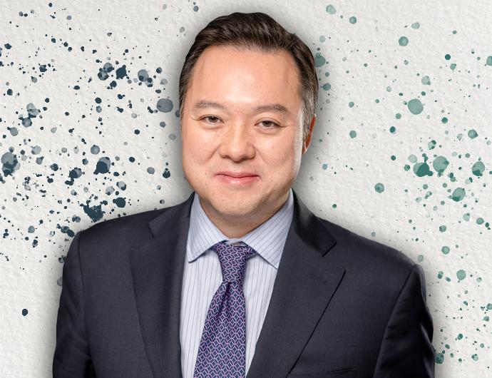 Headshot of AG William Tong in a dark navy suit overtop an off-white background with blue and green spatter